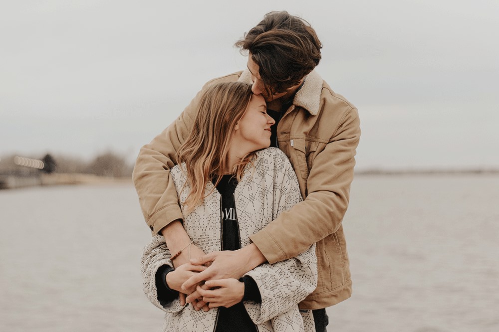 man hugging woman tenderly on the beach